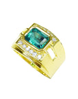 Gold ring with a bezel set natural emerald and small diamonds on a topside view profile.