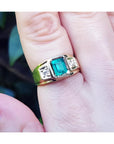 18k yellow gold ring for man with a natural colombian emerald and accent diamonds worn on a finger.