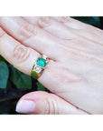 Gold men's ring with a Muzo colombian emerald on a hand against a natural background.