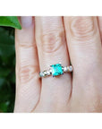 A hand wearing a ring with a natural colombian square emerald with accent diamonds in white gold.