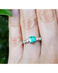 A hand wearing a ring with a natural colombian square emerald with accent diamonds in white gold.