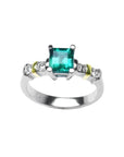 14K white gold ring with a square emerald cut Colombian emerald and side diamonds, accented with yellow gold.
