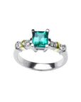 14K white gold ring with a square emerald cut Colombian emerald and side diamonds, accented with yellow gold.