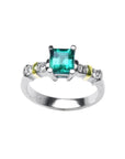 14K white gold ring with a square emerald cut Colombian emerald and side diamonds, accented with yellow gold.
