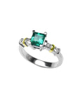 14K white gold ring with a square emerald cut Colombian emerald and side diamonds, accented with gold bands.