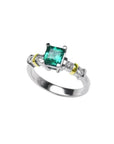 14K white gold ring with a square emerald cut Colombian emerald and side diamonds, accented with gold bands.