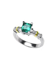 14K white gold ring with a square emerald cut Colombian emerald and side diamonds, accented with gold bands.