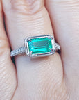 Emerald and accent diamonds ring white gold on a finger