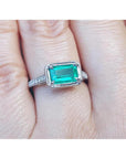 Emerald and accent diamonds ring white gold on a finger