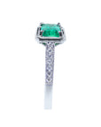A white gold natural emerald and diamond-studded band on a white background