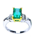Platinum emerald ring with side diamond accents on a white background.