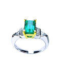 Platinum emerald ring with side diamond accents on a white background.