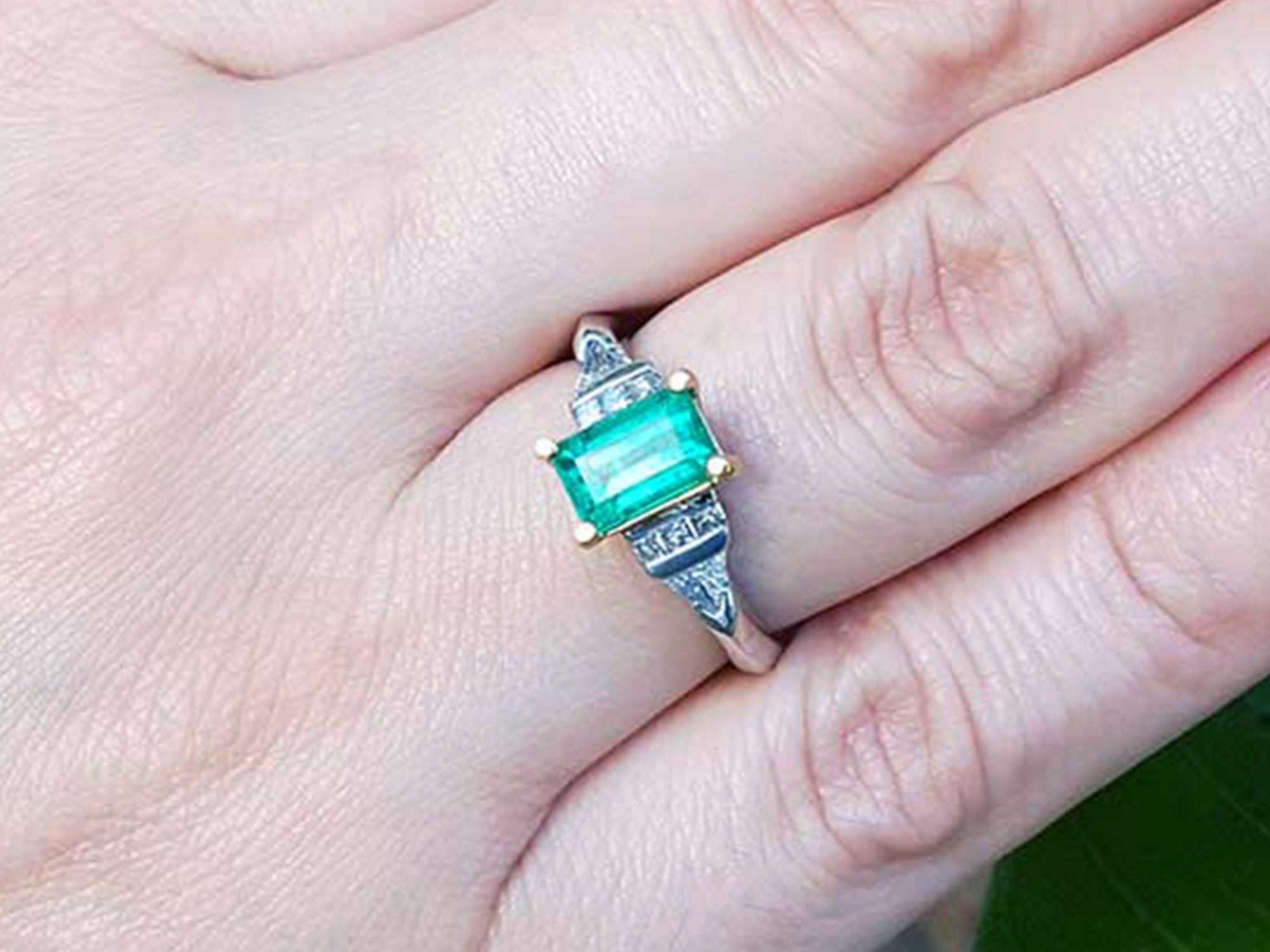 Close-up of a hand wearing an emerald ring with a natural colombian emerald.