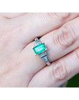 Close-up of a hand wearing an emerald ring with a natural colombian emerald.