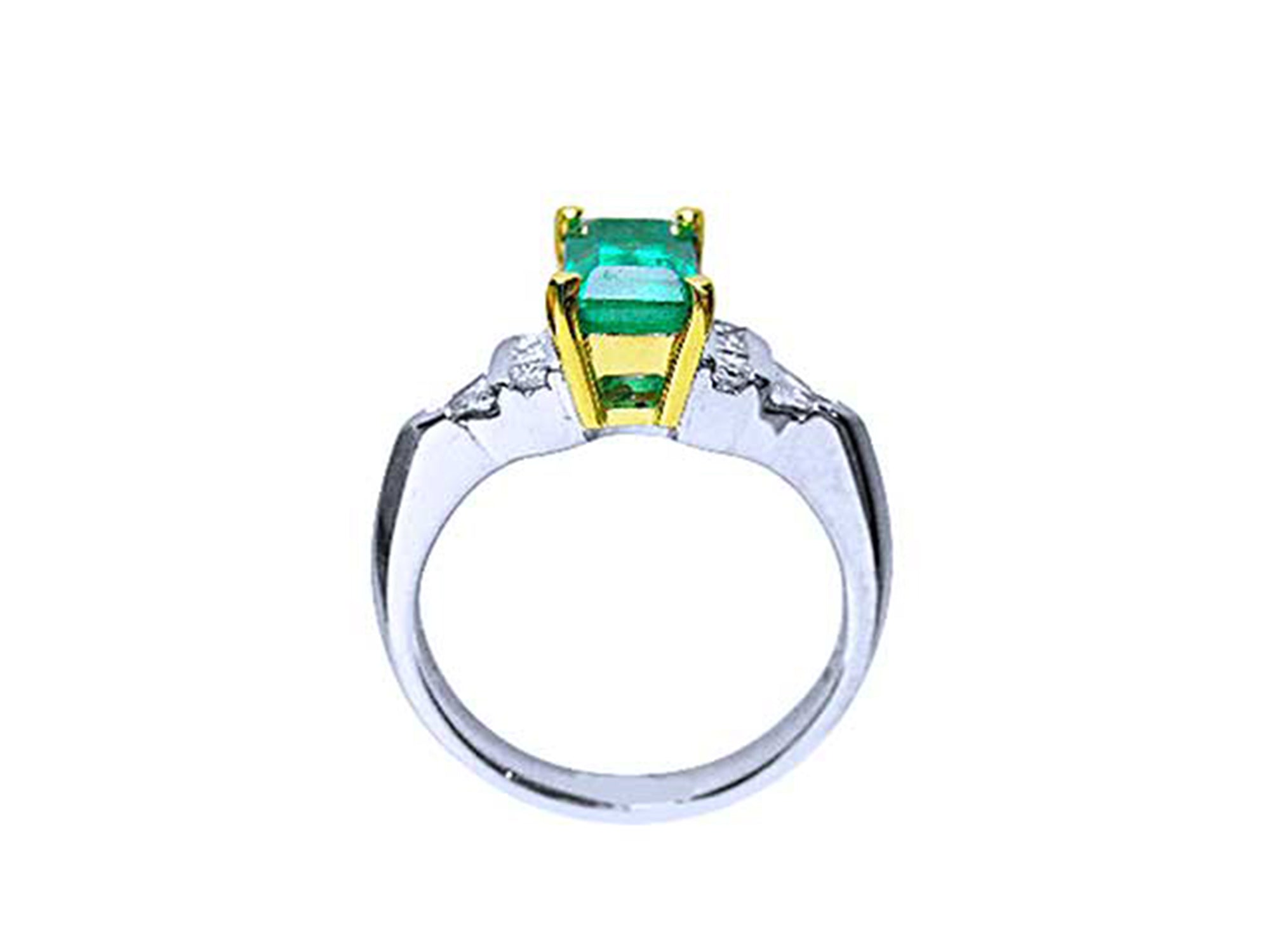 Platinum emerald ring with yellow gold setting on a white background.
