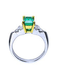 Platinum emerald ring with yellow gold setting on a white background.