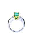 Platinum emerald ring with yellow gold setting on a white background.
