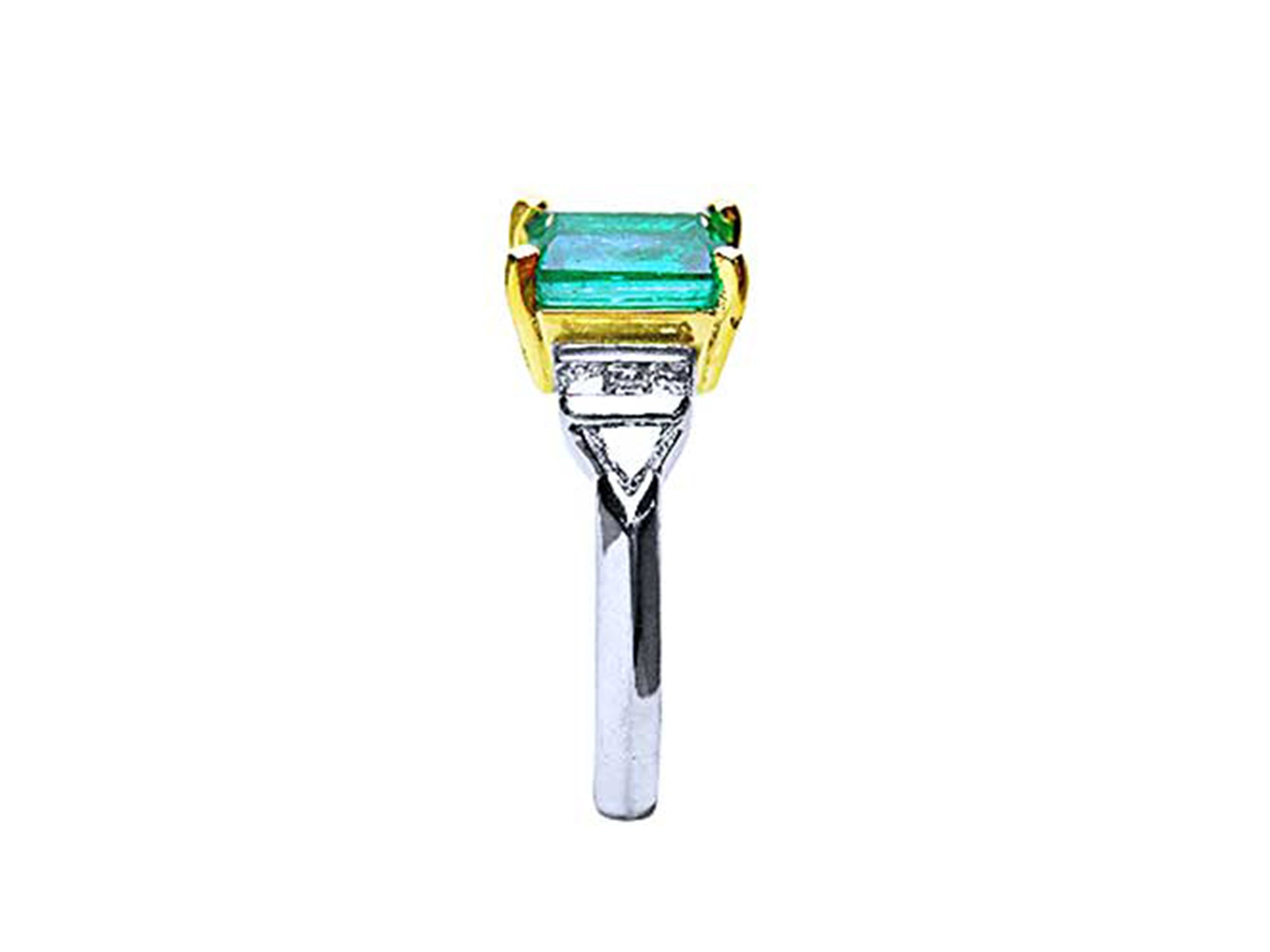 A side profile of a platinum emerald ring and accents on a white background.
