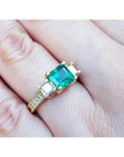 Yellow gold ring with a large emerald cut emerald and two princess cut side diamonds.