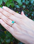 Hand wearing a May's birthstone ring for women against a leafy background