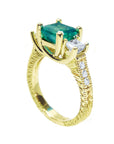 A half side profile of an emerald ring with side princess cut diamonds in 18k yellow gold.