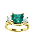 This emerald and princess cut side diamond three stone ring for women is made of 18k yellow gold.