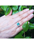 1.88 carat emerald ring with side emerald-cut and round diamonds in 18k white gold on a hand.