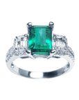 A tree stone emerald engagement ring with side emerald-cut diamonds in white gold, front top profile.