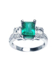 A tree stone emerald engagement ring with side emerald-cut natural side diamonds made of 18k white gold.