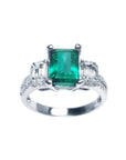 A tree stone emerald engagement ring with side emerald-cut natural side diamonds made of 18k white gold.