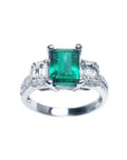 A tree stone emerald engagement ring with side emerald-cut natural side diamonds made of 18k white gold.