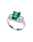 1.88 carat emerald ring with side emerald-cut and round diamonds in 18k white gold.