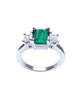 18k white gold three stone ring with a vibrant emerald and two princess cut diamonds.