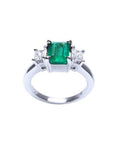 18k white gold three stone ring with a vibrant emerald and two princess cut diamonds.