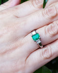 Emerald ring on a hand with a natural background.