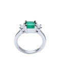 18k white gold three-stone ring with a 1.38 ct emerald and two princess-cut side diamonds.