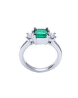 18k white gold three-stone ring with a 1.38 ct emerald and two princess-cut side diamonds.