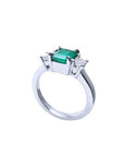 18k white gold three-stone ring with a rectangular emerald and two princess-cut side diamonds.