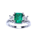 A three stone natural emerald ring for women with princess cut side diamonds in 14k white gold.