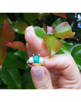 1.88 carat emerald ring with side emerald-cut diamonds and round accents in 18k white gold.