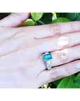 Emerald-cut emerald ring for women in 18K white gold with diamond accents on a hand.
