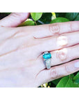 Emerald-cut emerald ring for women in 18K white gold with diamond accents on a hand.