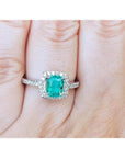 Women's cushion cut emerald ring with diamond halo and band in 14K white gold.