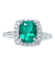 This emerald engagement ring cushion cut displays the full top view of the gemstone and the halo diamond.