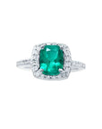 Cushion cut emerald ring with diamond halo and band in 14K white gold.