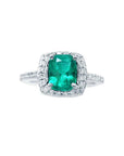 Cushion cut emerald ring with diamond halo and band in 14K white gold.