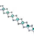 A white gold bracelet with round cut natural emeralds on a white background.