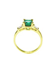 A Colombian emerald on top with side baguettes and gallery gold ring profile visibles including the band.