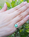 Hand wearing a natural emerald ring with a natural background.