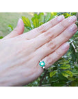 Hand wearing a natural emerald ring with a natural background.